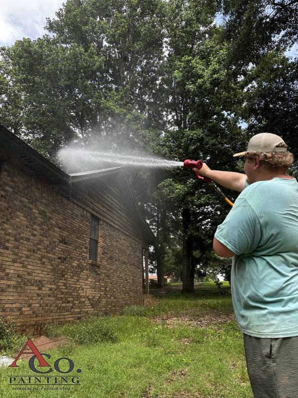 Soft washing a home exterior at low pressure to remove mildew and algae